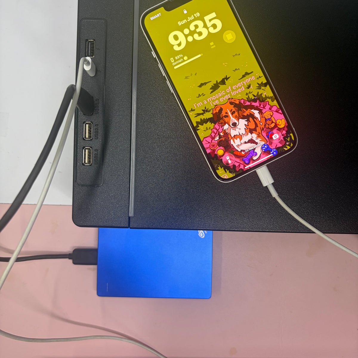 Phone charging wirelessly on the Command riser's surface while an external drive plugs into its USB hub